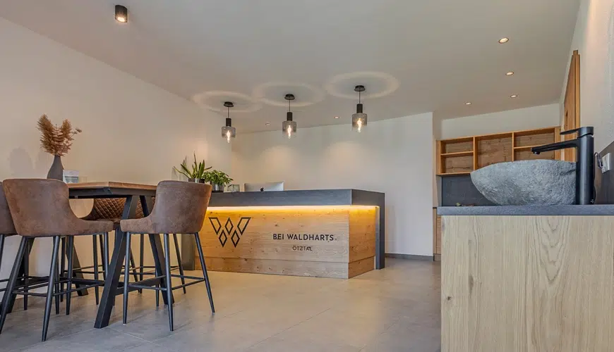 Modern reception area with wooden desk, pendant lights, and a small table with chairs.