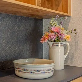 Floral pitcher and matching bowl evoke Holidays in the Ötztal on a dark countertop.