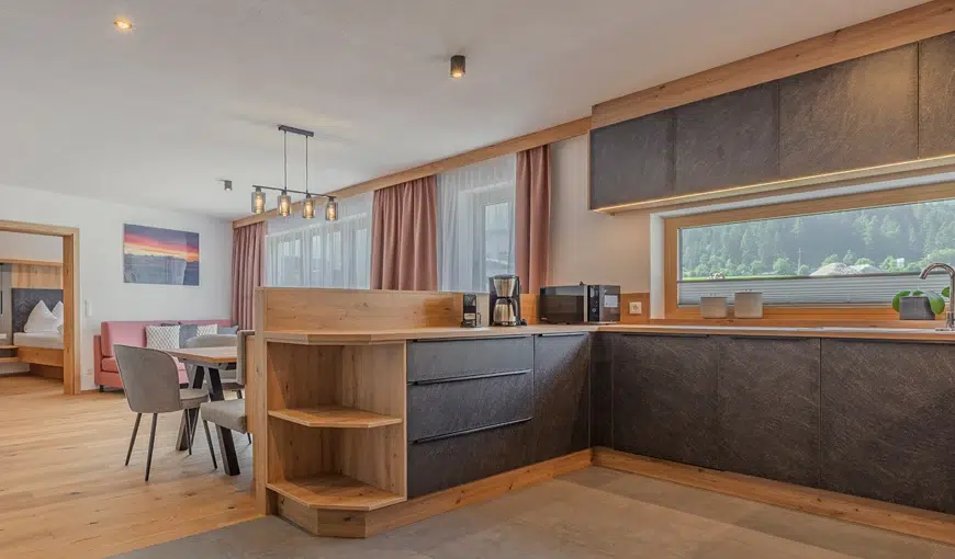 Modern kitchen and dining area with wood accents, large window, and natural light.